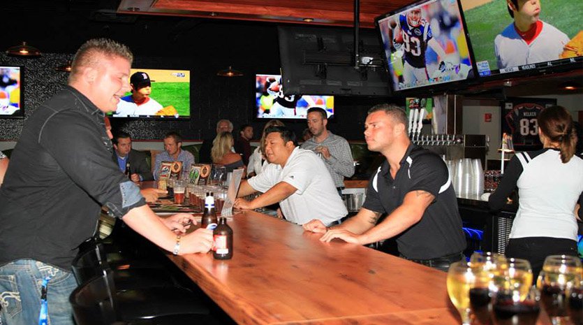 Crowded sports bar with patron ordering from bartender