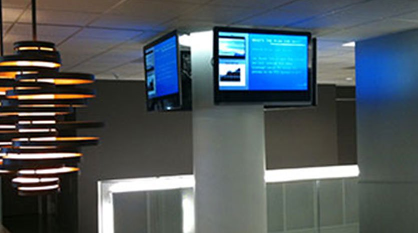 Video displays high up on a pillar next to a designer light fixture